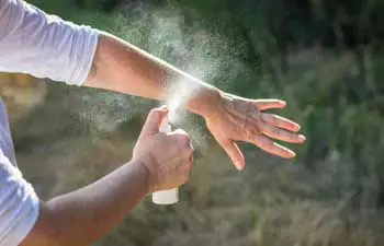 image of man using insect repellent