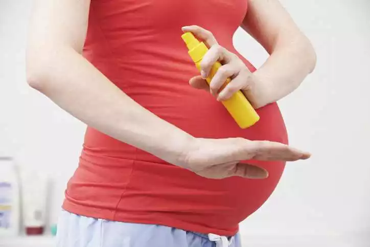 image of pregnant woman using insect spray repellents